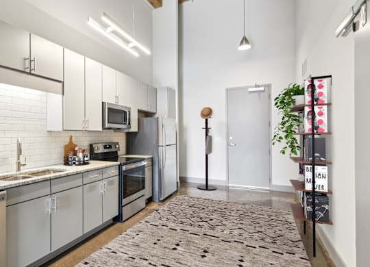 Vitually staged kitchen with stainless steel appliances, granite countertops, gray cabinetry and stone floors in Converse Mill Apartments in Spartanburg, SC.