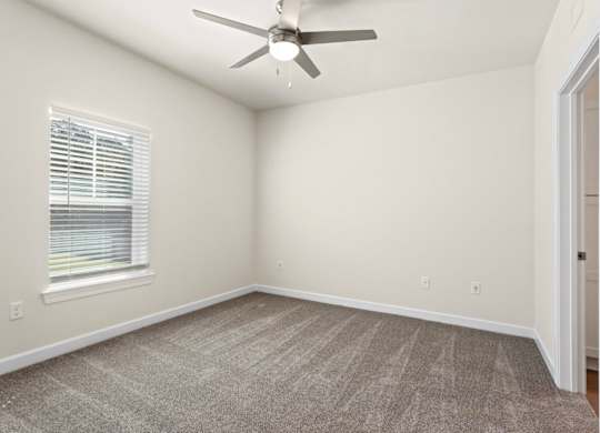 Peaks of Lexington Apartments Bedroom with Ceiling Fan, Light, Window and Gray Carpet and Connected Bathroom