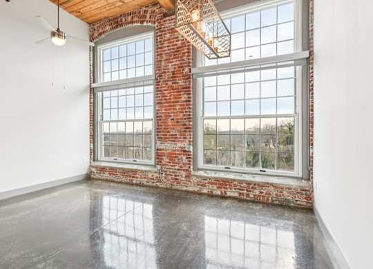 Living room with high ceilings and large windows at Converse Mill Loft Apartments in Spartanburg, SC