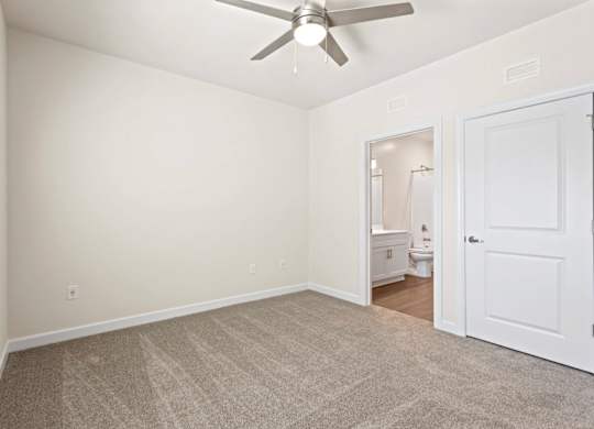 Peaks of Lexington Apartments Bedroom with Ceiling Fan, Light, Window and Gray Carpet and Connected Bathroom