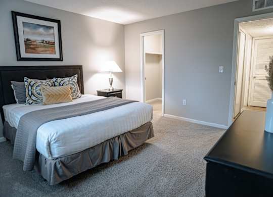 A bedroom with a large bed and a painting on the wall.