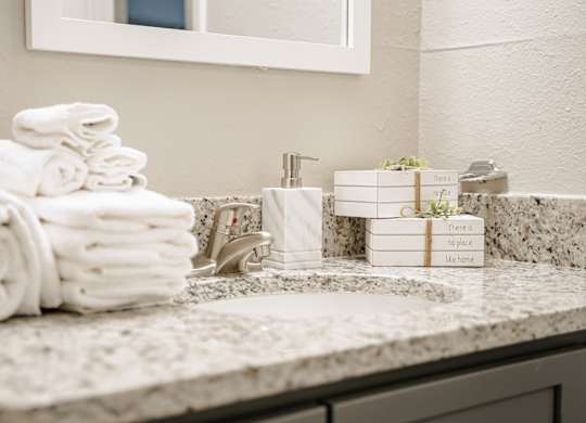 A stack of white towels sits on a marble countertop next to a soap dispenser.
