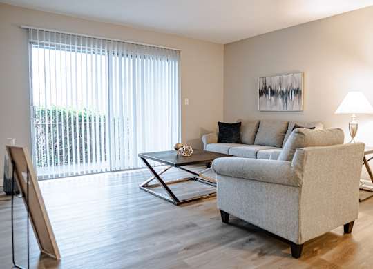 A living room with a couch, a coffee table, and a painting on the wall.