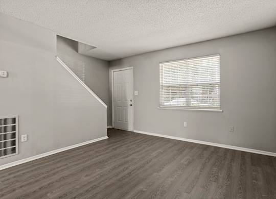 A room with a staircase and a window with blinds.