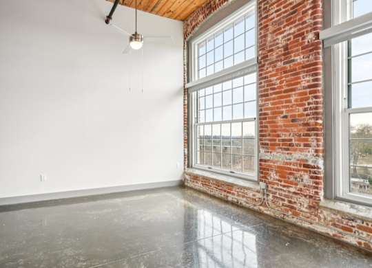 Living room with high ceilings and large windows at Converse Mill Loft Apartments in Spartanburg, SC