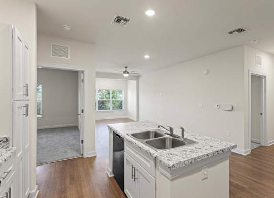Peaks of Lexington Apartments Kitchen with Black Appliances, Granite Countertops and White Cabinetry and connected living room
