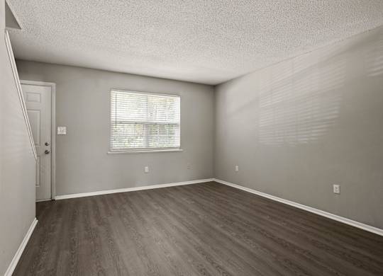 A room with wooden flooring and a window with blinds.