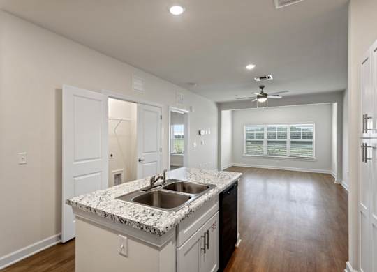 Peaks of Lexington Apartments Kitchen with Black Appliances, Granite Countertops and White Cabinetry and connected living room