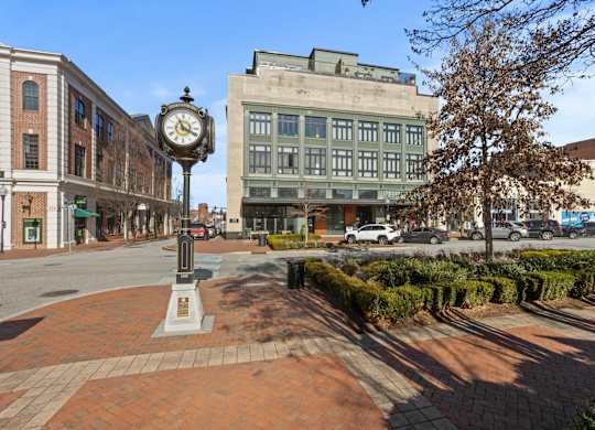Exterior view of Aug Smith on Main, an apartment community in Spartanburg SC, from the view of the park across the street. A street clock is prominently featured.