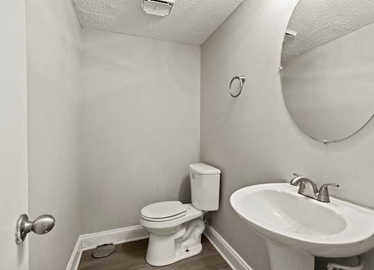 A bathroom with a toilet, sink and mirror.