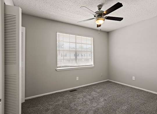 A room with a ceiling fan and a window with blinds.