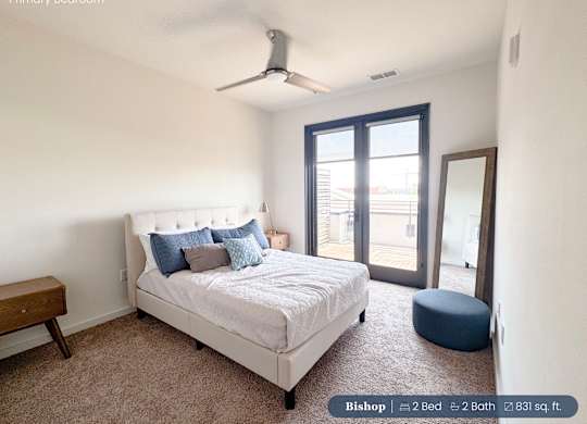 A bedroom with a bed, a bench, and a window.