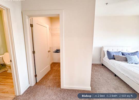 A bedroom with a bed, a chair, and a doorway leading to another room.