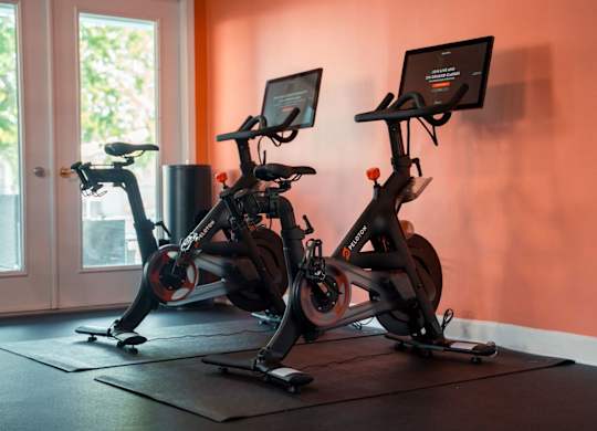 Two stationary bikes are set up in a room with a window.