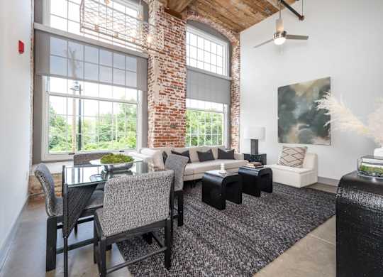 Converse Mill Lofts Luxury Apartments Model Unit Living Room with High Ceilings and Exposed Wood and Brick
