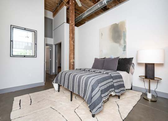 Converse Mill Lofts Luxury Apartments Model Unit Staged Bedroom with high ceilings, exposed beams