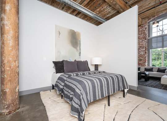 Converse Mill Lofts Luxury Apartments Model Unit Staged Bedroom with high ceilings, exposed beams