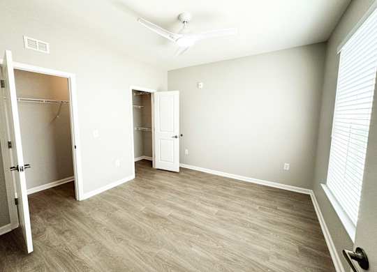 A room with a white door and a white closet with a white ceiling fan.