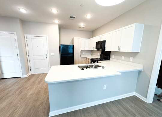 A kitchen with a white island and black appliances.