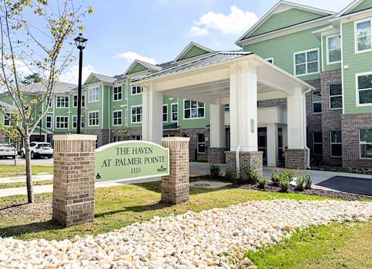 The Haven at Palmer Pointe Senior Apartments Entrance with carport and a sign that reads "The Haven at Palmer Pointe"