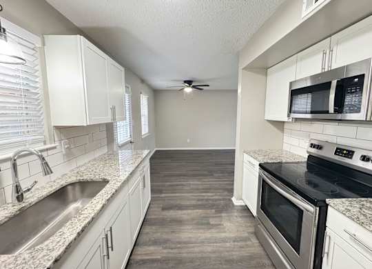 Reserve at Hillcrest Townhomes kitchen with granite countertops, white cabinetry and stainless steel appliances