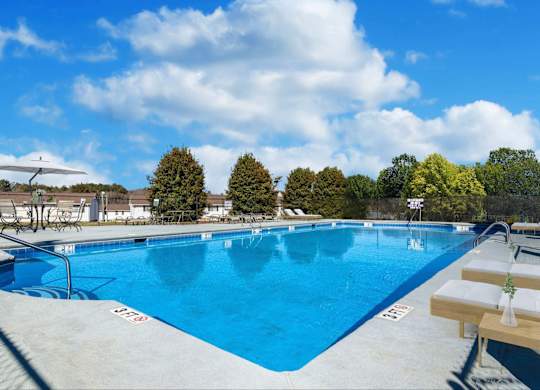 Reserve at Hillcrest Townhomes blue 3-4 foot pool with deck and chairs