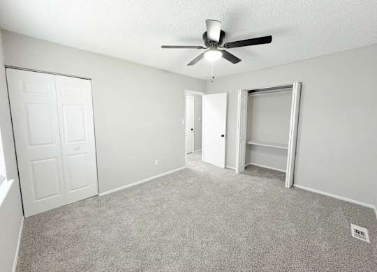 Reserve at Hillcrest Townhomes bedroom with two closets, gray carpet, and a ceiling fan with a light