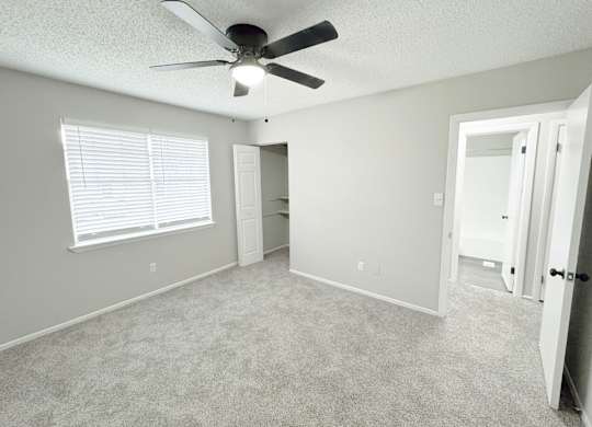 Reserve at Hillcrest bedroom with closet with shelves, a gray carpet, a window, a ceiling fan and a light