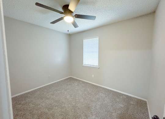 Reserve at Hillcrest Townhomes bedroom with carpet, a window with blinds and a ceiling fan with light