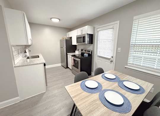 Reserve at Hillcrest Townhomes furnished kitchen with granite countertops, stainless steel appliances, and a dining room table.