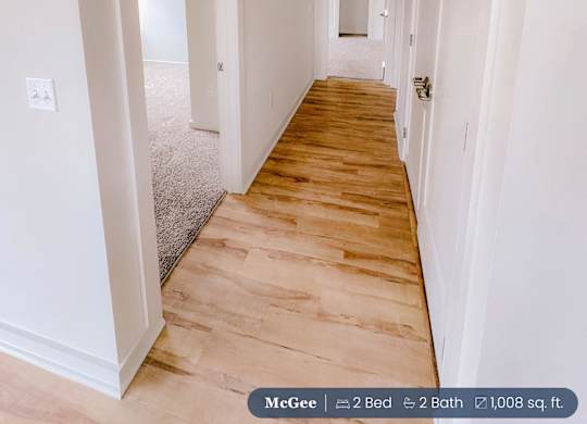 A long hallway with wood floors and white walls.