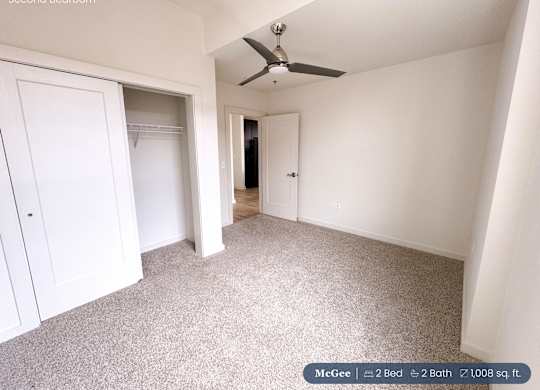 A second bedroom with a carpeted floor and a ceiling fan.