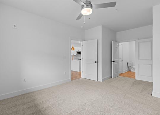 A room with a ceiling fan and carpeted floor.