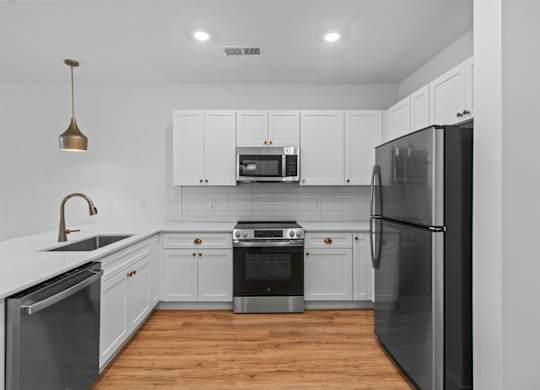 A modern kitchen with white cabinets and stainless steel appliances.