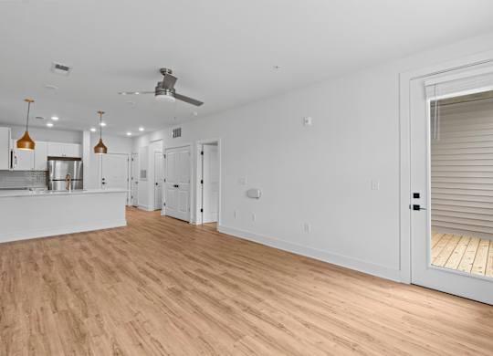 A spacious room with wooden flooring and white walls.