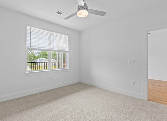 A room with a ceiling fan and a window with blinds.
