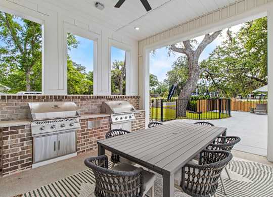 A patio with a table and chairs and a grill.