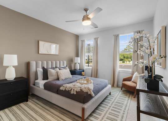 A bedroom with a large bed and a ceiling fan.