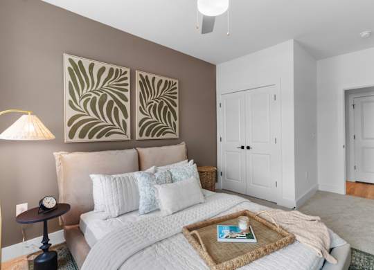 A bedroom with a large bed and two framed artworks on the wall.