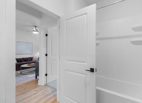 A white door is open to a room with a brown couch and a white wall.