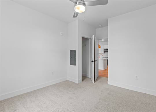 A room with a ceiling fan and a door leading to another room.