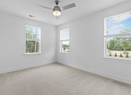 A room with a ceiling fan and two windows.
