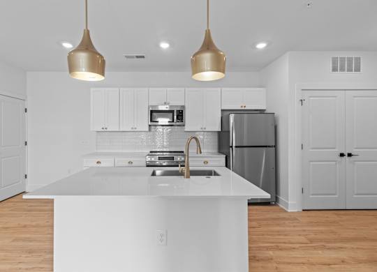 A modern kitchen with a white countertop and stainless steel appliances.