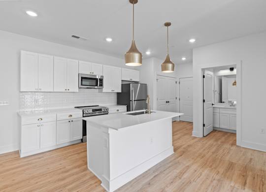 A modern kitchen with white cabinets and a wooden floor.