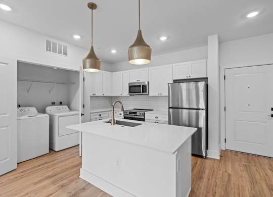A modern kitchen with a white island and stainless steel appliances.