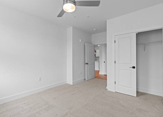 A room with a ceiling fan and carpeted floor.