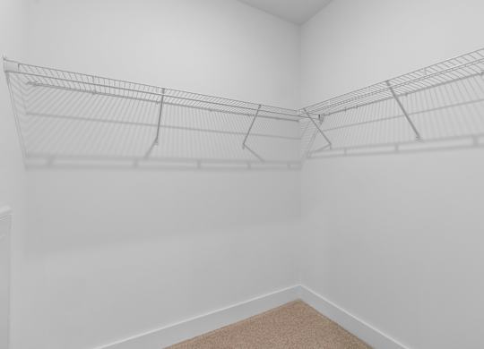 A white room with a carpeted floor and a wire shelving unit.