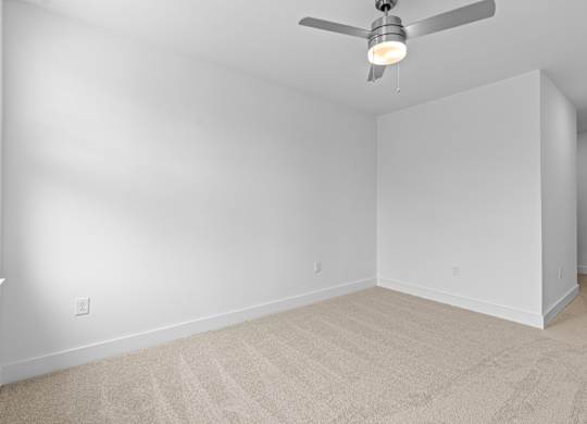 A room with a ceiling fan and carpeted floor.