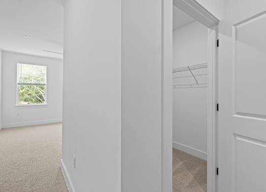A white hallway with a door on the right and a window on the left.