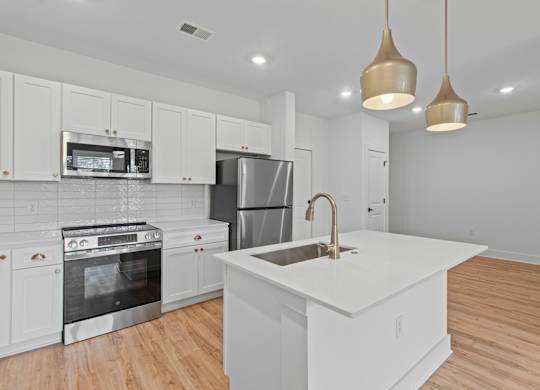 A kitchen with white cabinets and a white island.